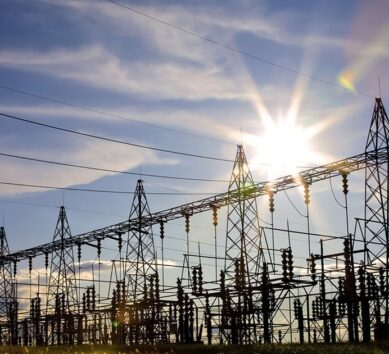 Sunset behind an extensive electrical substation with multiple high-voltage towers and power lines, illustrating the energy industry.